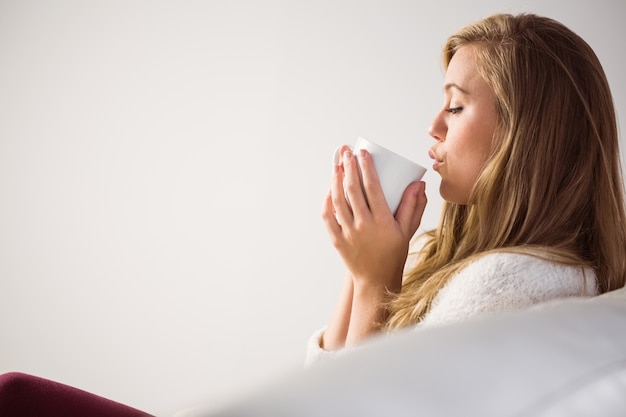 Pretty blonde relaxing on the couch with tea