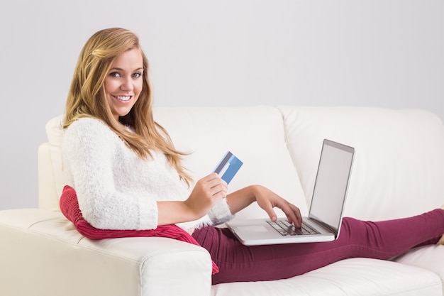 Pretty blonde relaxing on sofa with laptop