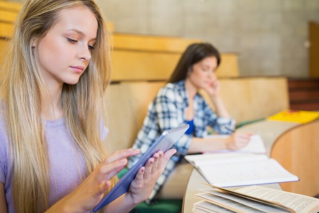 Studente biondo grazioso che utilizza compressa nell'università