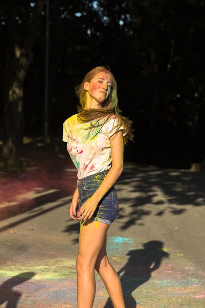 Pretty blonde woman celebrating Holi festival in the park