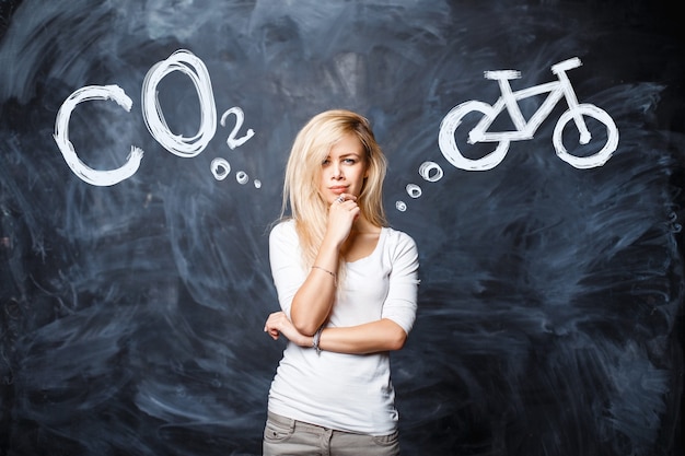 Pretty blonde woman chooses between co2 gas pollution of nature and healthy transport by bicycle