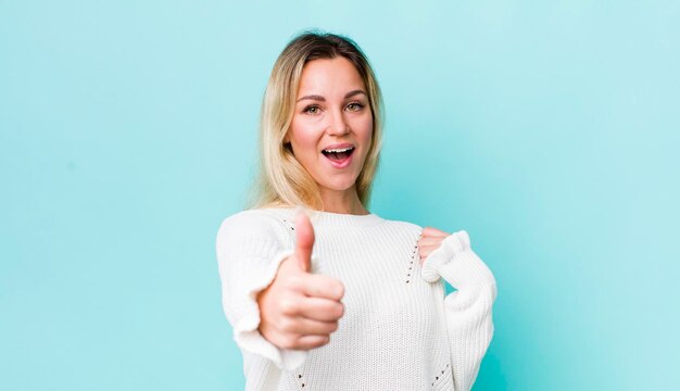 Pretty blonde woman feeling proud carefree confident and happy smiling positively with thumbs up