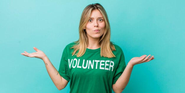 Pretty blonde woman feeling puzzled and confused and doubting volunteer concept