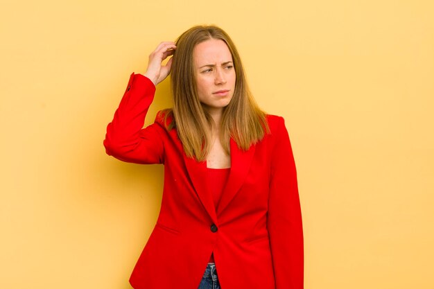 Pretty blonde woman feeling puzzled and confused scratching head businesswoman concept