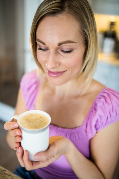 Donna bionda graziosa che mangia caffè