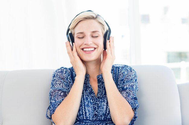 Pretty blonde woman listening music on the couch