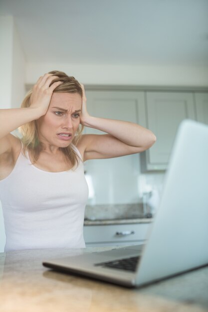 Donna bionda graziosa che esamina computer portatile