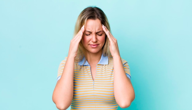 Bella donna bionda che sembra stressata e frustrata che lavora sotto pressione con mal di testa e turbata da problemi