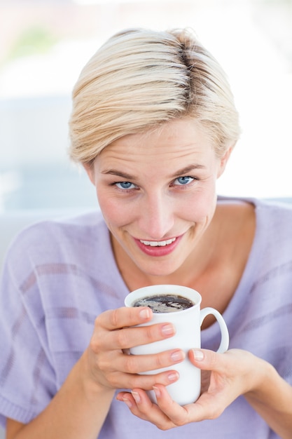 Photo pretty blonde woman relaxing on the couch and holding a mug