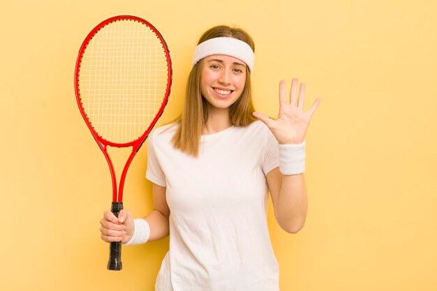 笑顔でフレンドリーに見えるきれいなブロンドの女性は、5番目のテニスのコンセプトを示しています