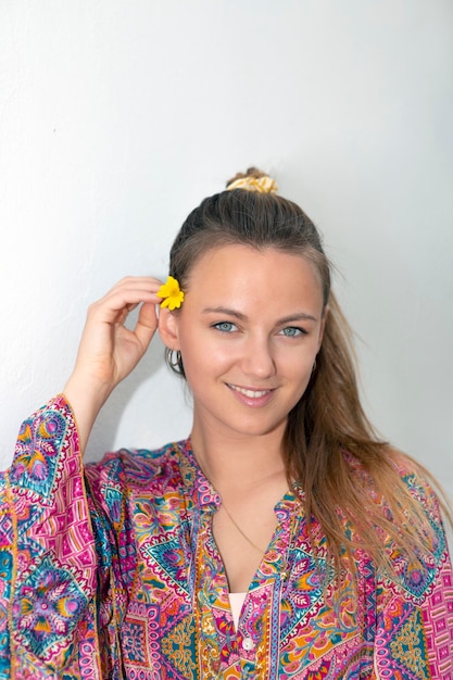 Pretty blonde woman with daisy in hair on white background