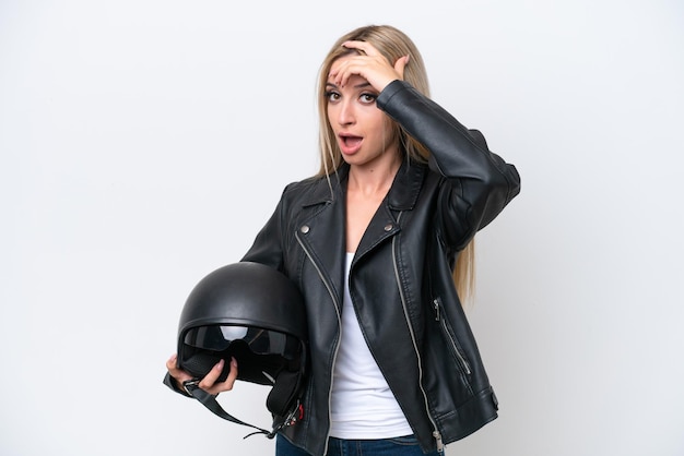 pretty blonde woman with a motorcycle helmet isolated on white background doing surprise gesture while looking to the side