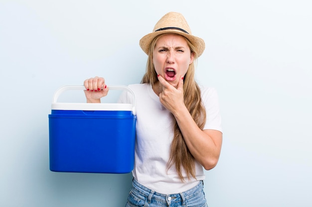 Pretty blonde young adult woman with a portable fridge summer picnic