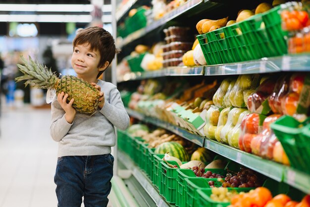 Pretty boy with pineapple in supermarket