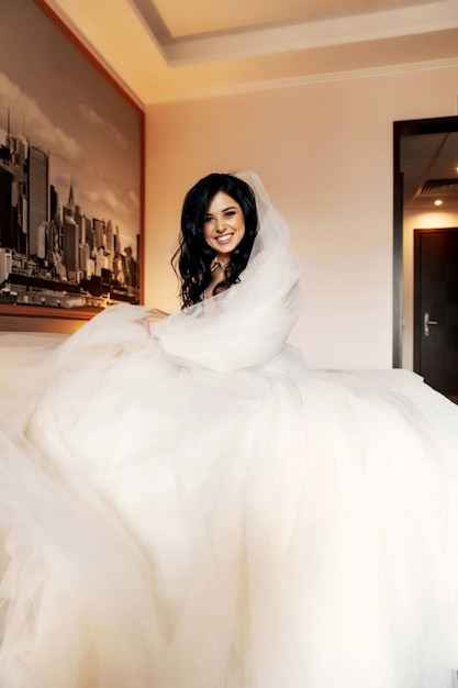 Photo pretty bride in her wedding dress posing indoors