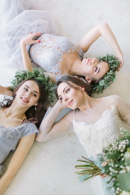 Pretty bride with bridesmaids are lying on the white floor