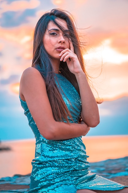 Photo a pretty brunette in a beautiful sunset in a blue bodycon dress