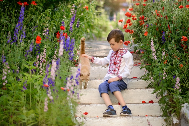 Pretty brunette boy 5-6 years old in a traditional costume in a poppy field in summer