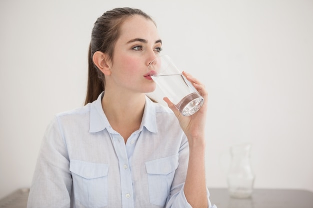 Pretty brunette drinking glass of water