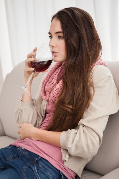 Pretty brunette drinking wine on couch