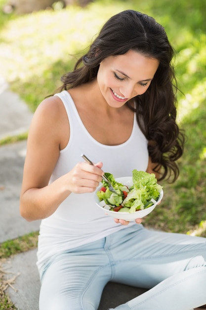 Pretty brunette eating bowl of salad