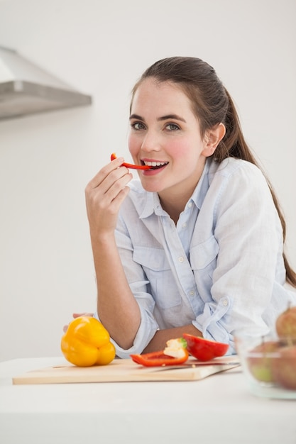 Pretty brunette eating sliced pepper