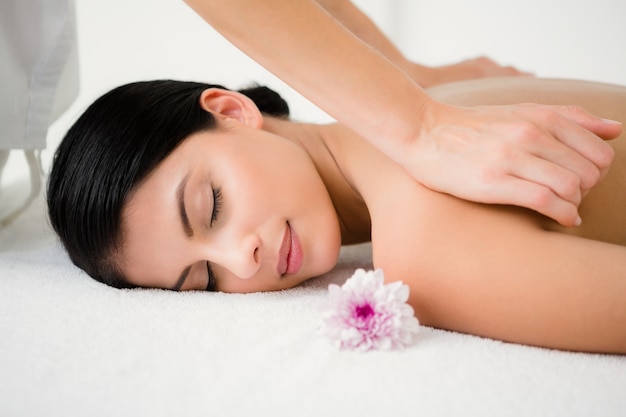 Pretty brunette enjoying a massage with flower