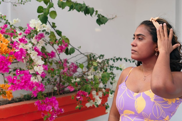 Pretty brunette girl posing in front of some flowers