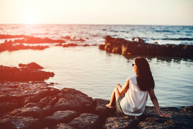 Foto ragazza graziosa del brunette che si distende nelle pietre