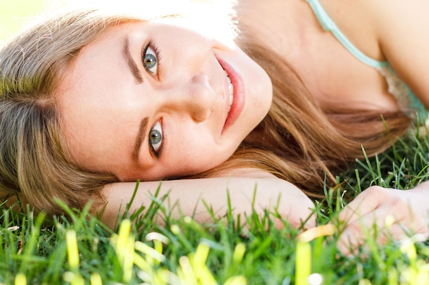 Pretty brunette girl wearing elegant dress relaxing outdoor in green grass and smells aromatic lemon or lime citrus