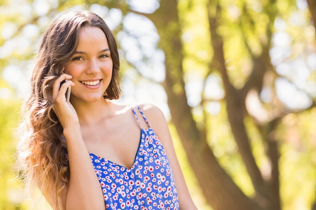 Pretty brunette having phone call in the park on a sunny day