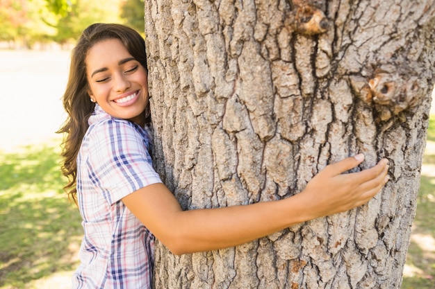 Pretty brunette hugging tree