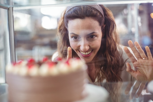 Pretty brunette looking at chocolate cake through the glass