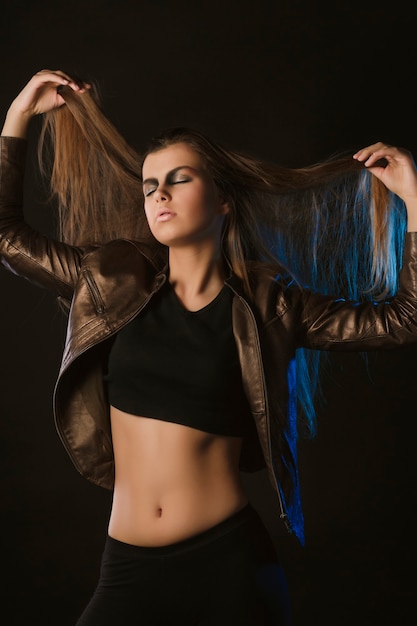 Pretty brunette model with long hair in leather jacket  at studio