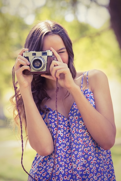 Pretty brunette in the park using retro camera