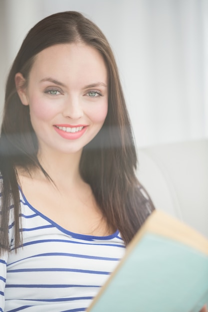 Pretty brunette reading book on couch