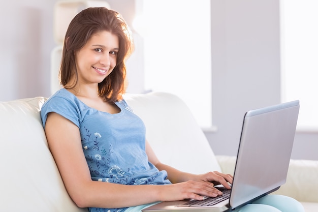 Pretty brunette relaxing on the couch using laptop