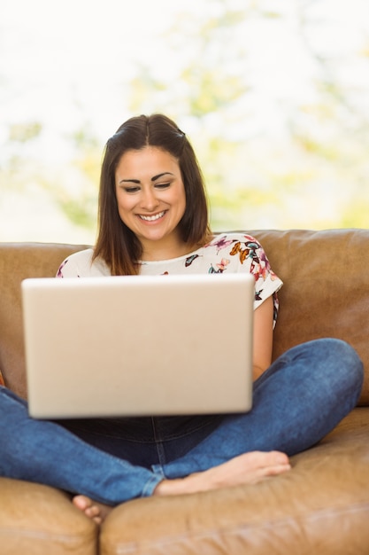 Pretty brunette relaxing on couch with laptop 