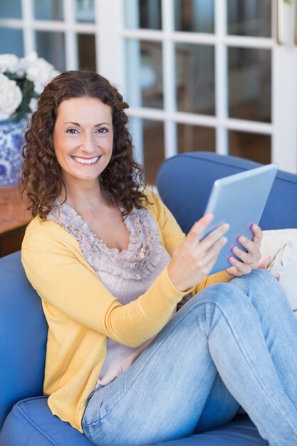 Pretty brunette relaxing on the couch with tablet