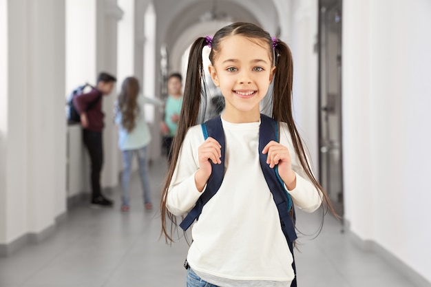 かなりブルネットの学校の女の子の幸せな笑顔