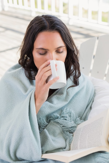 Pretty brunette sitting on a chair and drinking coffee in patio