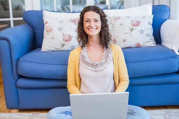 Pretty brunette sitting on the floor and using her laptop