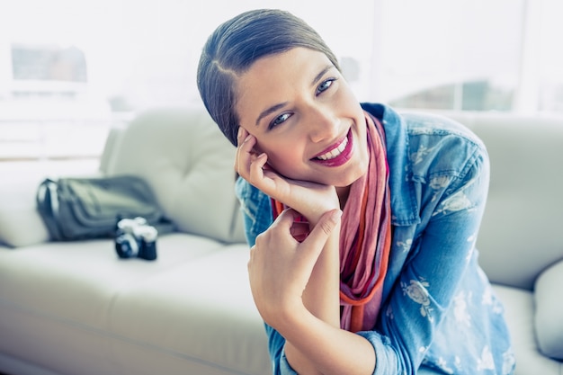 Pretty brunette sitting on sofa looking at camera