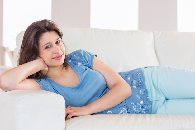 Pretty brunette smiling at camera on the couch