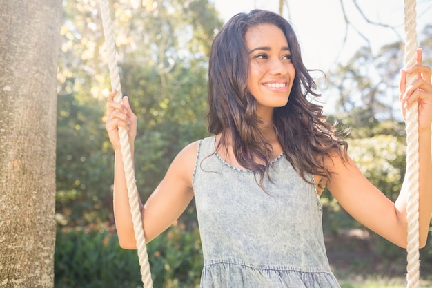 Pretty brunette swinging in park 