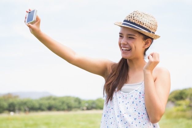 Pretty brunette taking a selfie in park