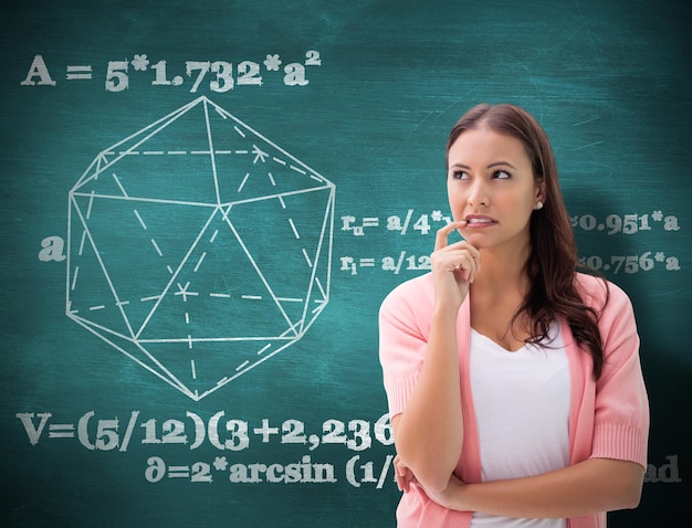 Photo pretty brunette thinking with finger to mouth against green chalkboard