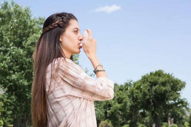 Pretty brunette using her inhaler 