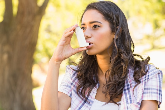 Pretty brunette using inhaler