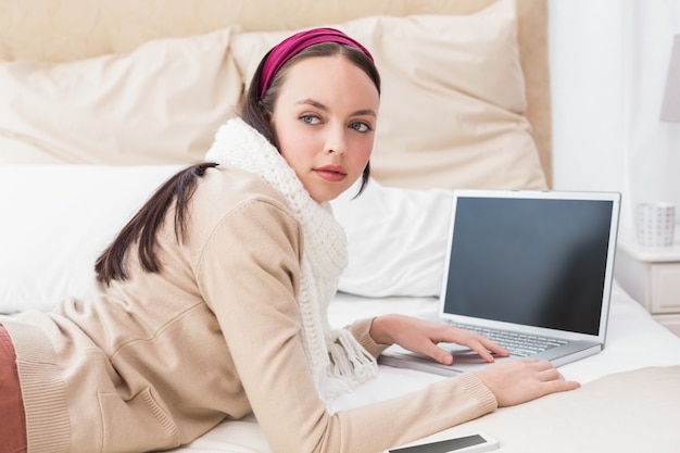 Pretty brunette using laptop on bed